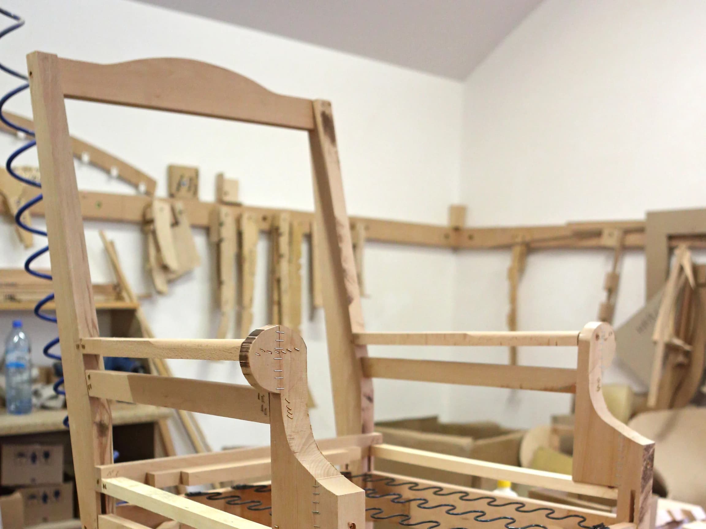 An unfinished sofa frame in raw beech wood, showing the joinery and hand-tied support springs before upholstery.